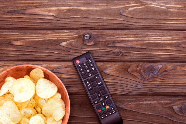 puces, tv à distance sur un fond de table en bois. - appetizer bowl potato chip condiment photos et images de collection