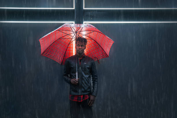 雨の下で赤い傘を持つ男 - serious african ethnicity mid adult bright ストックフォトと画像