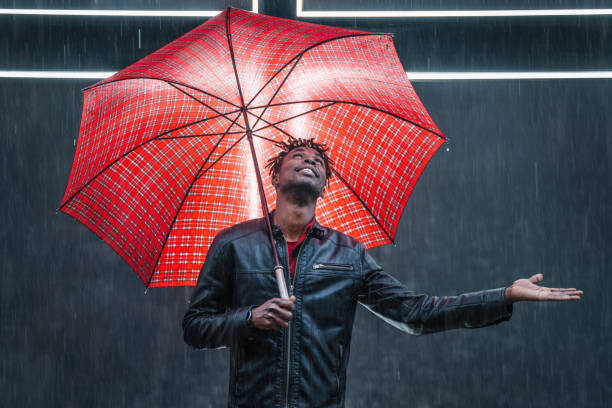 Man with red umbrella under rain stock photo