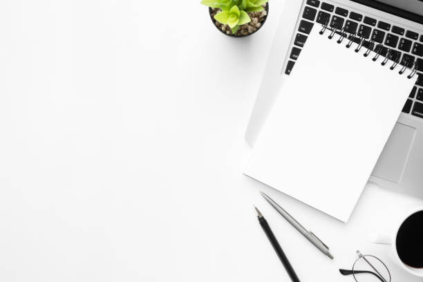 istock White office desk table with notebook over a laptop computer with coffee and supplies. Top view with copy space, flat lay. 1146704916
