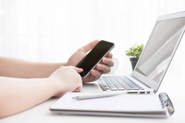istock Hands using and touching smartphone screen over white office desk table with laptop and office supplies. Business concept. 1146704923