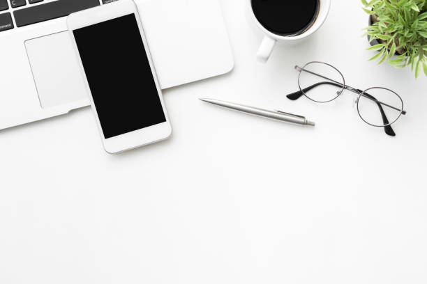 istock White office desk table with smartphone with blank mock up screen, laptop computer and supplies. Top view with copy space, flat lay. 1146704924