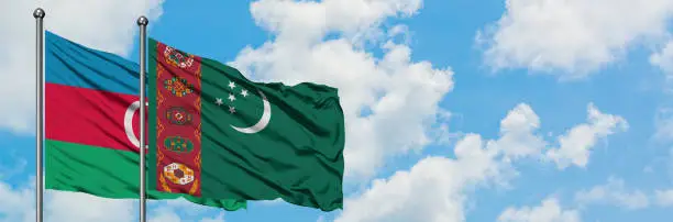 Photo of Azerbaijan and Turkmenistan flag waving in the wind against white cloudy blue sky together. Diplomacy concept, international relations.