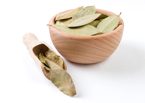 bay leaves in wooden bowl isolated on white background. Spices and food ingredients.