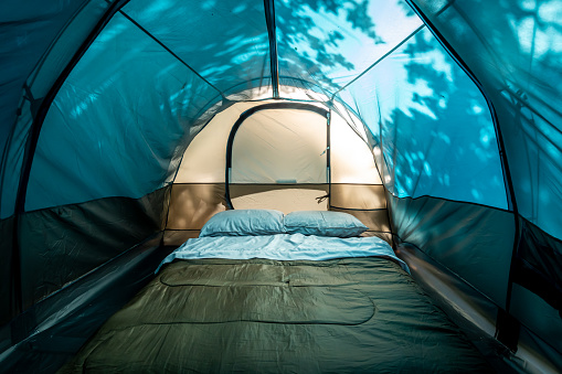 Inside view of a camping tent with inflatable bed, sleeping bag and pillows on a sunny day in Florida.