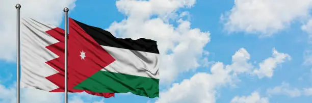 Bahrain and Jordan flag waving in the wind against white cloudy blue sky together. Diplomacy concept, international relations.