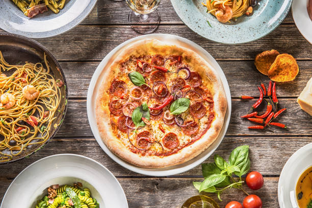 top of view full table of italian meals on plates and pan. pizza pasta risotto soup and fish vegetable salad - basil tomato soup food and drink imagens e fotografias de stock