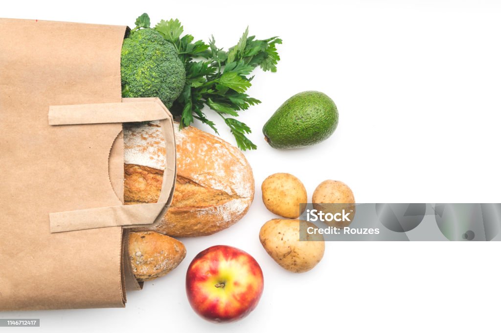 Full paper bag of different health food on white Top view paper bag of different fresh health food on white background. Supermarket Stock Photo