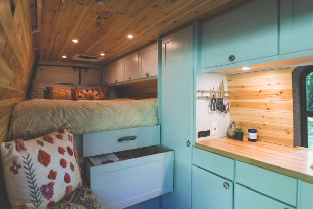 Interior of a live-in van Interior of a van that a young couple live in. The shot is focused on the kitchen counter, pull-out drawers, and bed. Ther is wood paneling on the sides and roof. tiny house stock pictures, royalty-free photos & images