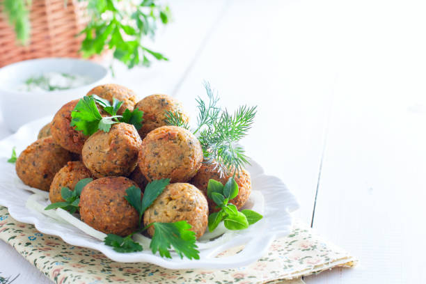 Falafel patty being dipped into a cucumber and mint dip