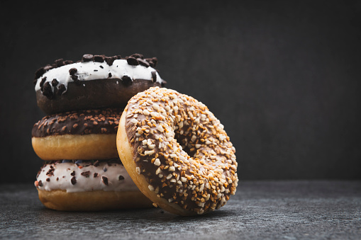 Stack of assorted donuts on dark background, copy space