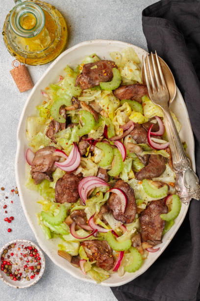 warm salad of chicken (duck, goose, rabbit) liver, iceberg lettuce, red onion, celery and fried mushrooms with dressing of olive oil, soy sauce and granular mustard. selective focus - vinegar salad dressing balsamic vinegar olive oil imagens e fotografias de stock