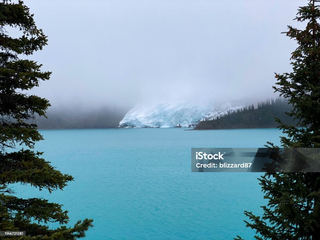 Mount Robson glacier A view from the trees onto Mount Robson glacier, behind a cloud of fog across the Berg Lake. Beauty Stock Photo