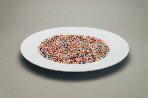 istock White plate with color preparations (vitamins, dyes, flavor enhancers, nutritional supplements, innovative technologies, candy sweets) on a gray background. 1146725535