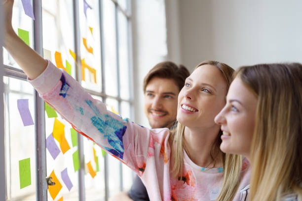 Woman placing sticky note on window in the day