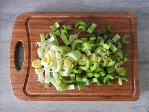 frische grüne sellerie-stämme auf holzschnittbrett in der nähe. - caulis stock-fotos und bilder