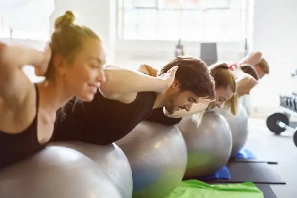 Group of people having gymnastic exercises with inflatable balls at gym