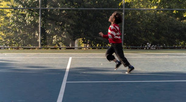 der 7-jährige junge spielt am sonnig warmen frühlingstag auf dem tennisplatz im park. - six speed stock-fotos und bilder
