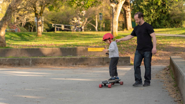 istock Father teaching his 7-years-old son how to ride an electrical skateboard. Stanley Park in Vancouver, Canada. The sunny warm spring day. 1146728725