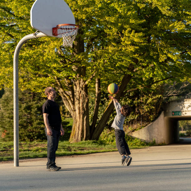 padre e suo figlio di 7 anni che giocano a basket nello stanley park, vancouver, canada - 6 7 years foto e immagini stock