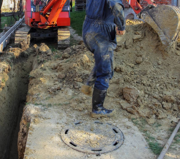 istock A worker working on sewer ditch cleaning his rubber boots, small excavator in the background. 1146731907