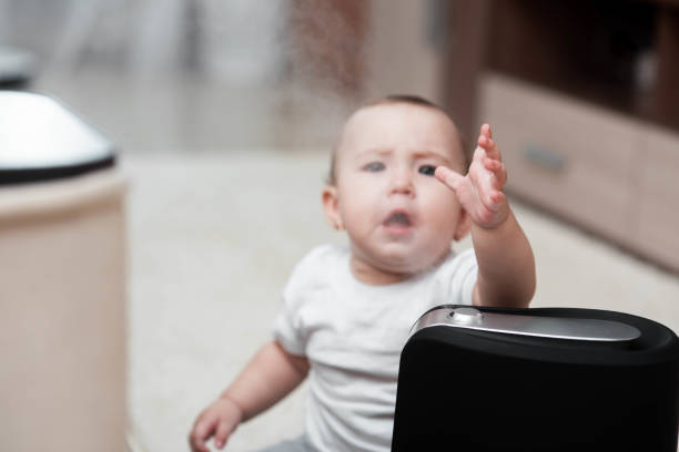 il bambino guarda l'umidificatore. l'umidità nel concetto di casa - contemporary domestic room sparse indoors foto e immagini stock