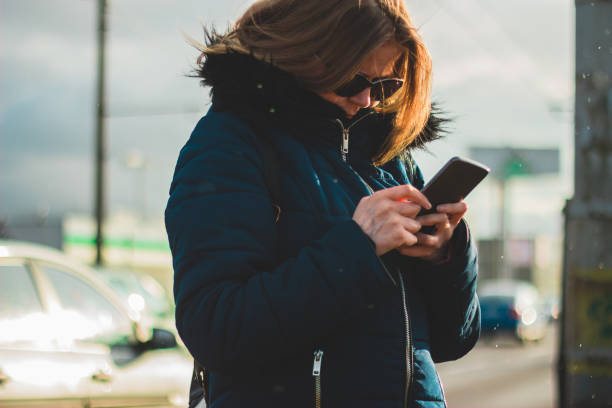 istock Woman using her smartphone on a cold day 1146733883