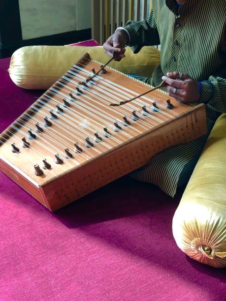 Stock photo of man playing santoor instrument in India. Made of wood with up to 100 strings, santoors provide traditional background music in restaurants. imagen del músico indio tocando el instrumento santoor con cuerdas como la guitarra, la forma trapezoide de madera tradicional santoor instrumento musical indio con cuerdas siendo interpretado por el hombre músico hindú sentado, como la música dulcimer