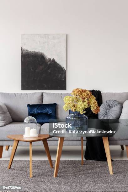 Blumen In Blauer Glasvase Und Zwei Weiße Kerzen Auf Holzkaffechtischen In Grauem Elegantem Wohnzimmer Mit Komfortablem Sofa Stockfoto und mehr Bilder von Grau