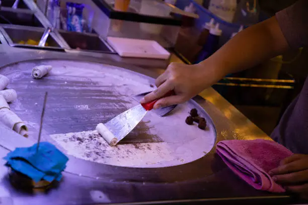 Photo of Woman hand making ice cream on round cold plate