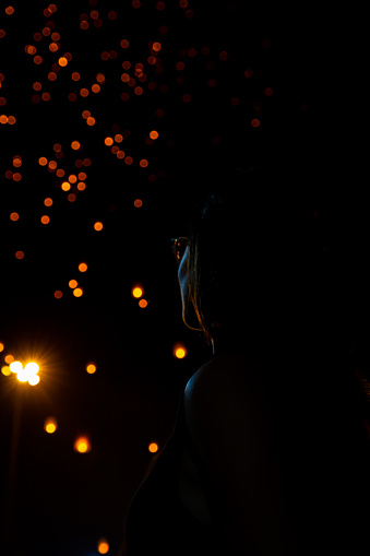 Beautiful woman looking at Loy Krathong paper lanterns as bokeh on background in Thailand