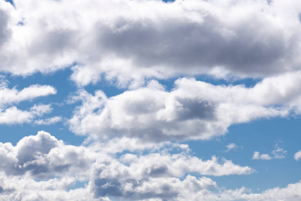Large (puffy, fluffy, cotton-like) white cumulus clouds and blue skies on a sunny afternoon in spring (in May) in Norway, captured with a prime, short telephoto/macro lens and a full frame digital camera at ISO 100 producing large clean files.