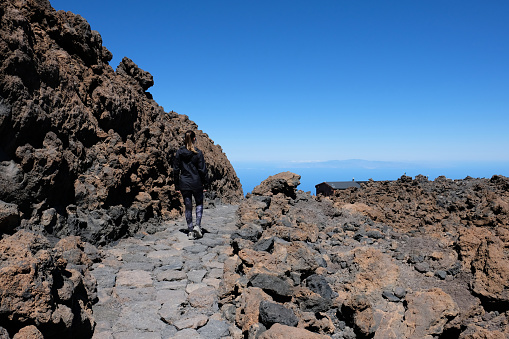 Woman descending the Teide mountain peak on a dry and rocky volcanic landscape