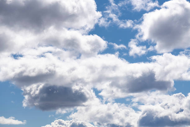 Large (puffy, fluffy, cotton-like) white cumulus clouds and blue skies on a sunny afternoon in spring (in May) in Norway, captured with a prime, short telephoto/macro lens and a full frame digital camera at ISO 100 producing large clean files.