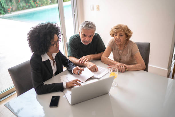 financial advisor helping a senior couple at home - finance senior adult financial advisor meeting imagens e fotografias de stock
