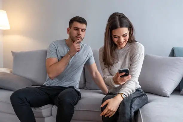 Photo of Man spying his girlfriend mobile phone.