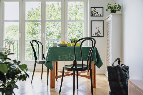 istock White dining room interior with table with coffee mug, fresh fruits and dark green tablecloth, two posters on white wall and balcony in real photo 1146741175