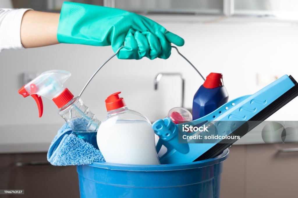 Cleaning Bucket Woman holding cleaning products with glove. Cleaning Stock Photo