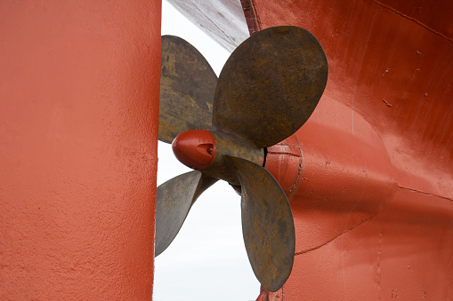 a rusty red fishing boat propeller in dock