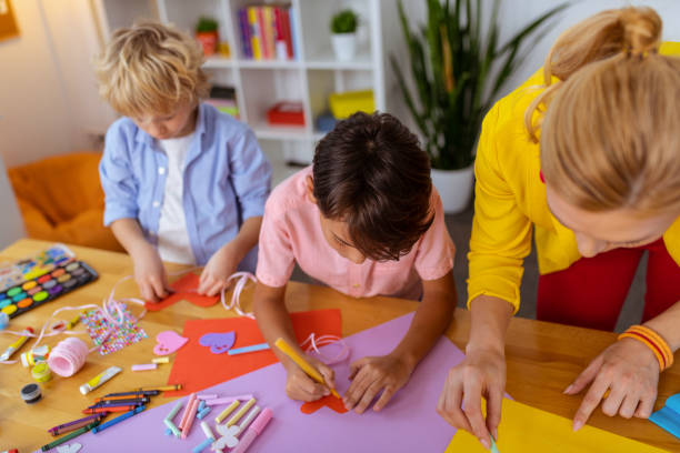 istock Boys standing near teacher while making cutouts and painting 1146747295