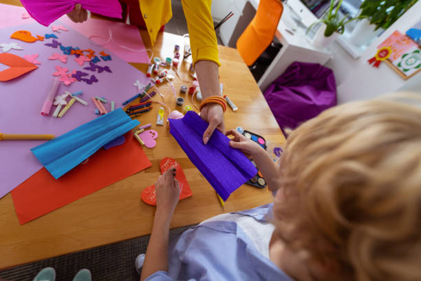 istock Teacher giving blue paper for schoolboy making applied ornament 1146747310