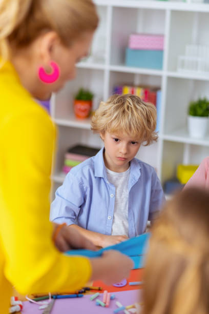 istock Schoolboy looking at teacher making applied ornament 1146747314