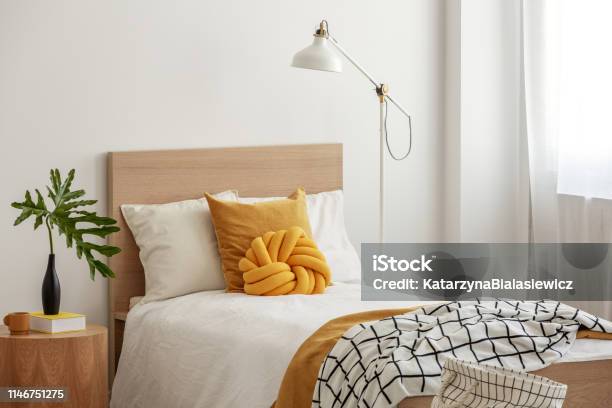 Yellow Pillows And Cozy Blanket On Single Bed In Elegant Hotel Roomgreen Leaf In Black Vase On Wooden Bedside Table Stock Photo - Download Image Now