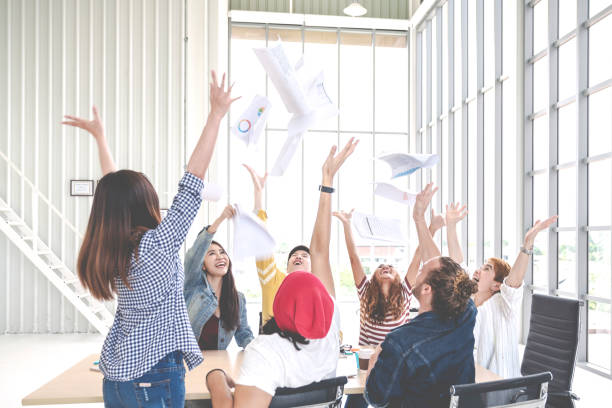 istock Candid group of young creative team employee prople throwing documents paper and feeling happy after work success at working place in office. Asian business team celebrating a good job. Soft tone 1146754967