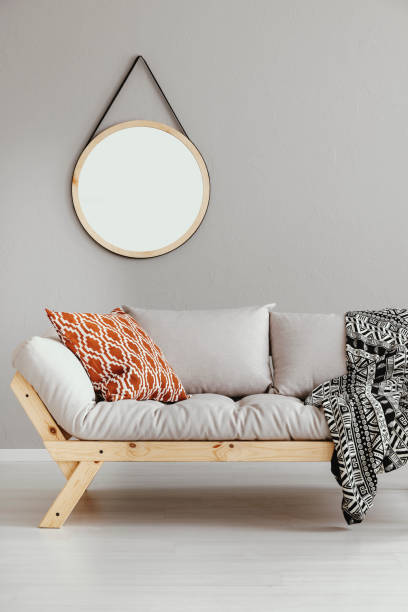 istock Round mirror hanging on the wall in bright living room interior with light grey sofa with cushion and blanket in real photo 1146756773