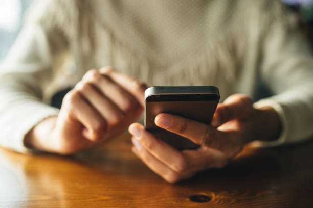 istock Woman using smartphone on wooden table in cafe 1146758619