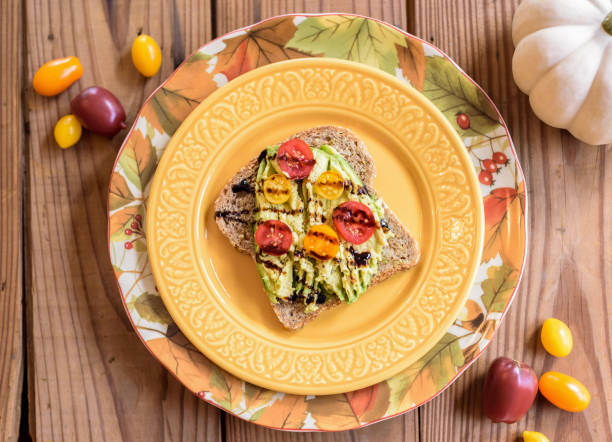 Fall food flat lay - avocado toast on yellow plate with fresh ingredients