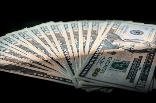 Closeup of US twenty dollar bills fanned out on black background