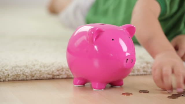Young boy putting money in piggy bank