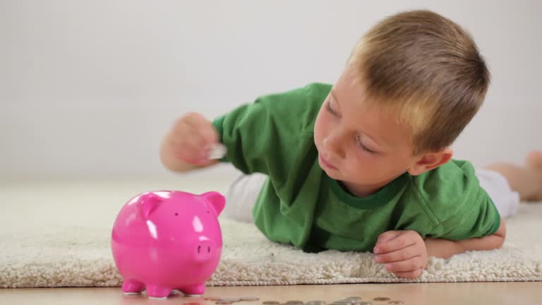 Young boy putting money in piggy bank